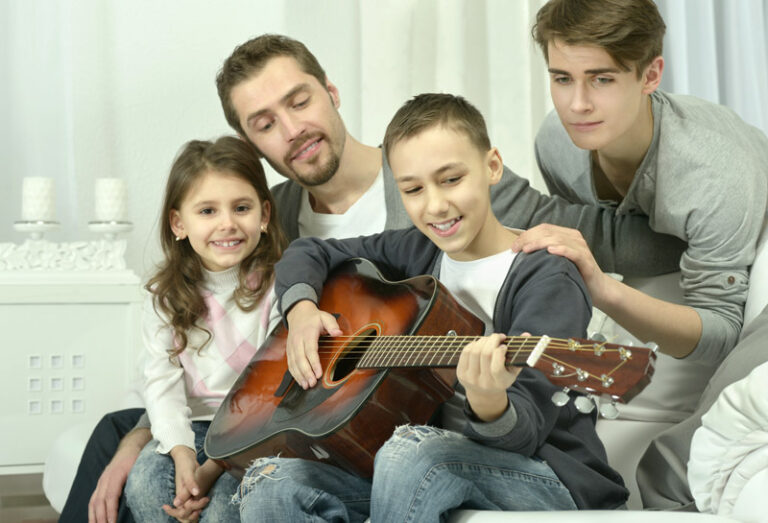 boy  playing the guitar for his family