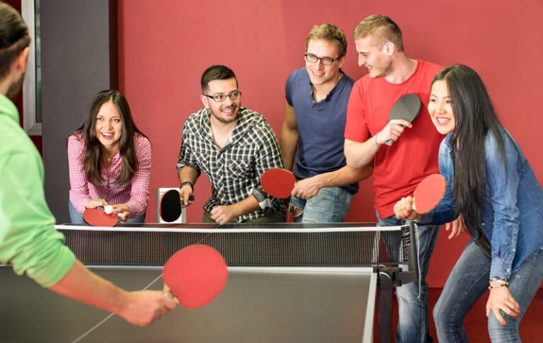 Group of happy young friends playing ping pong table tennis - Fu