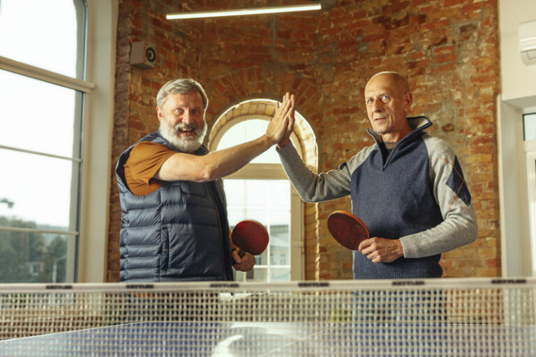 Senior men playing table tennis in workplace, having fun